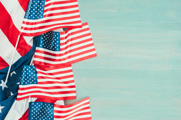 bovenaanzicht van ingerichte Amerikaanse vlaggen op blauwe houten tafelblad, voorzitters dag concept - Foto, afbeelding