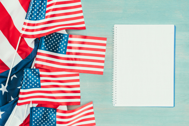 vista superior de las banderas estadounidenses dispuestas y cuaderno en blanco sobre mesa de madera azul, concepto de día de presidentes
 - Foto, imagen