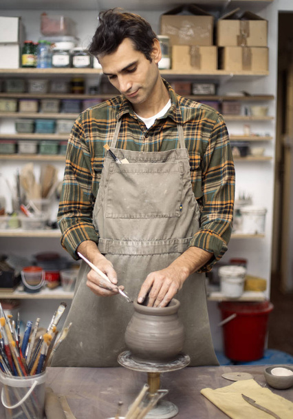 Junger Mann töpfert und dekoriert in Werkstatt - Foto, Bild