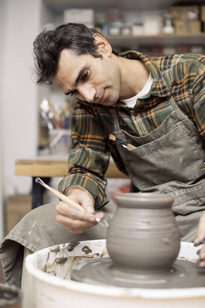 View at an artist makes clay pottery on a spin wheel in workshop - Photo, Image