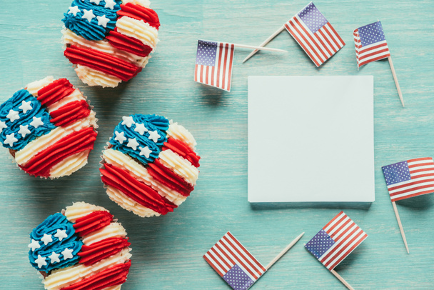 vlakke leggen met gearrangeerde cupcakes en Amerikaanse vlaggen op houten tafelblad, voorzitters dag viering concept - Foto, afbeelding