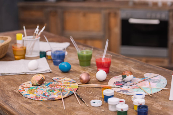 painted chicken eggs with paints and brushes on wooden table, easter concept - Photo, Image