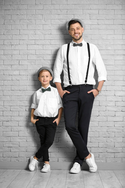 Father and son in elegant suits against brick wall - Фото, зображення