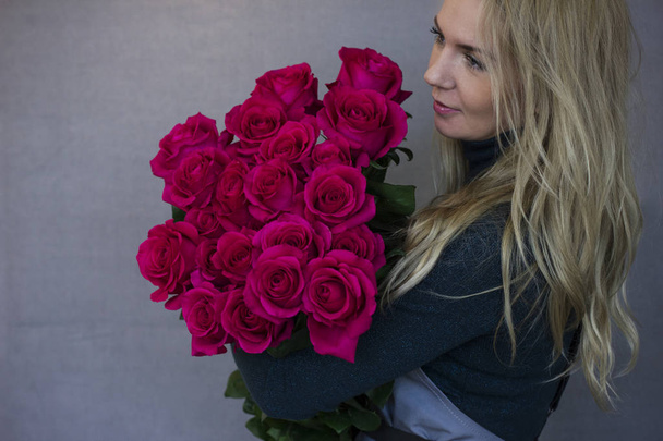 Belle jeune femme tenant un grand bouquet de roses roses
 - Photo, image
