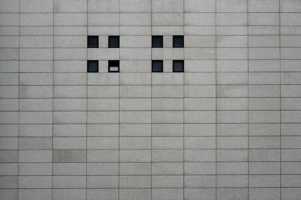 Fachada moderna com pequenas janelas quadradas / A fachada moderna de um moderno edifício comercial e comercial com lajes de concreto retangular e pequenas janelas quadradas
.                          - Foto, Imagem