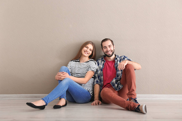 Young couple sitting on floor in empty room. Ready for moving to new house - Foto, Imagen