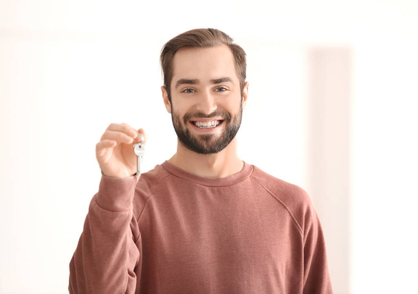 Young man holding keys of his new house, indoors - Foto, Bild