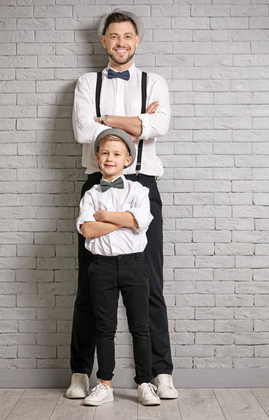 Father and son in elegant suits against brick wall - Φωτογραφία, εικόνα