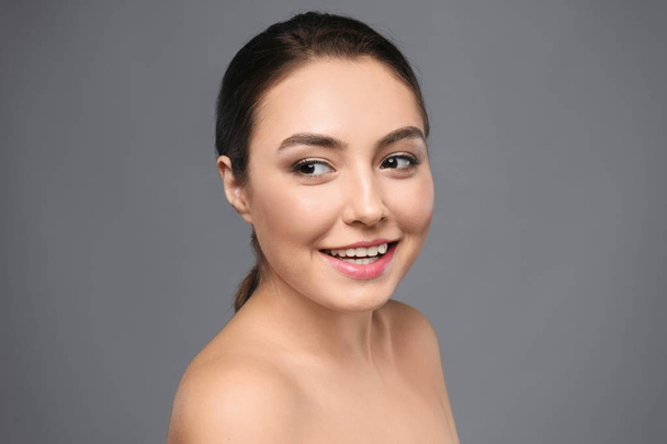Portrait of beautiful young woman with clear skin on grey background - Valokuva, kuva