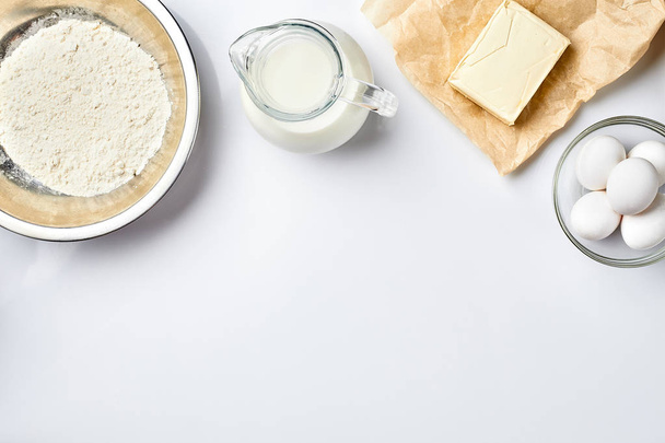 Preparação da massa. Uma medida da quantidade de ingredientes na receita. Ingredientes para a massa: farinha, ovos, leite, manteiga, creme. Vista superior, espaço para texto
 - Foto, Imagem