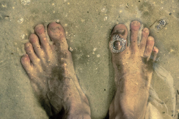 πόδια κάτω από το νερό που στέκεται σε αμμώδη βυθό και φυσαλίδες σε wat - Φωτογραφία, εικόνα
