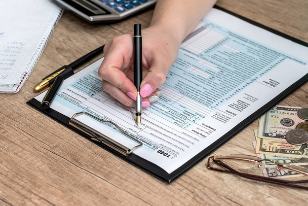 Kobieta, wypełniając formularz podatkowy pieniędzy i Kalkulator - Zdjęcie, obraz