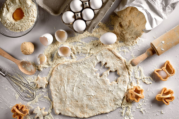 Concept de cuisson : pâte crue pour biscuit, œufs, farine, découpeuses en forme d'étoile et papillon sur une table blanche. Vue du dessus
. - Photo, image
