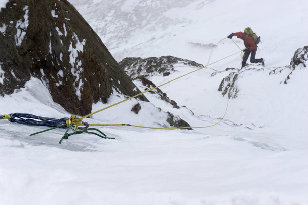 arrampicatore di montagna maschio che si stacca da un filo a V con un back-up mentre si ritira da un'alta vetta nelle Ande peruviane con maltempo in arrivo
 - Foto, immagini