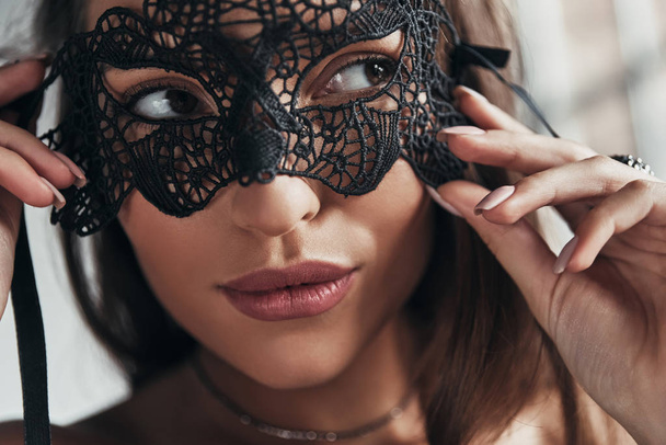 close up portrait of gorgeous woman wearing black carnival mask on eyes - Foto, Imagem