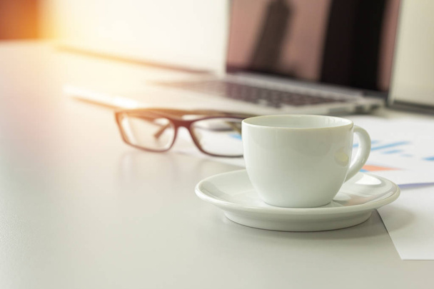 Крупный план кофе чашка на столе с ноутбуком, очки и бумаги в б
 - Фото, изображение
