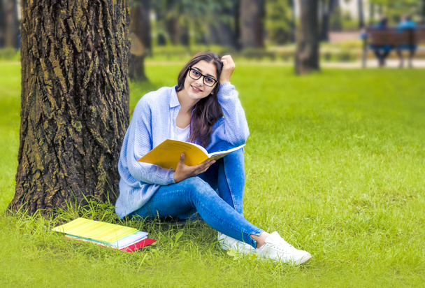 Όμορφη φοιτήτρια, ινδική γυναίκα, γυαλιά, διαβάζοντας ένα βιβλίο. - Φωτογραφία, εικόνα
