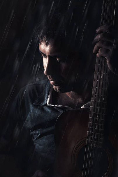 ο άνθρωπος με μια κιθάρα σε μαύρο φόντο - Φωτογραφία, εικόνα
