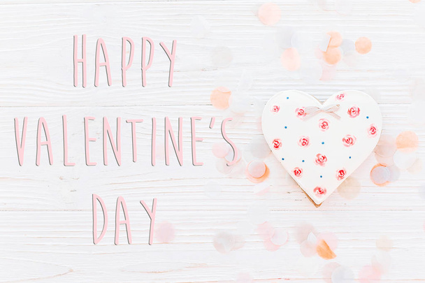 幸せなバレンタインデーのテキスト記号フラットなレイアウト。ピンク クッキー心と白の素朴な木製の背景に紙吹雪。テキストのためのスペース。グリーティング カードのコンセプトです。バレンタイン明るいイメージ - 写真・画像