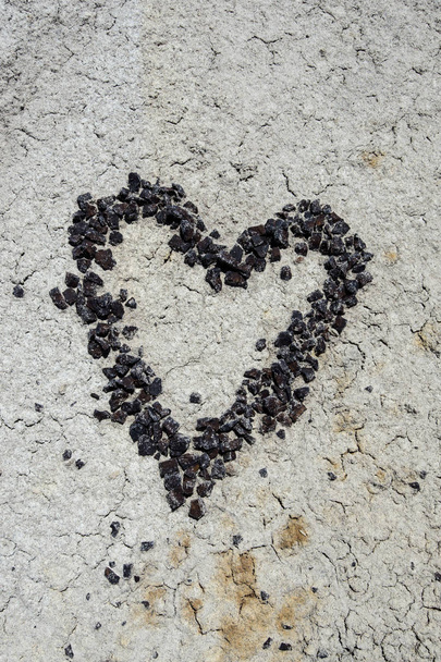 cuore fatto di ciottoli di pietra rossa su uno sfondo di terra crepa secca
 - Foto, immagini