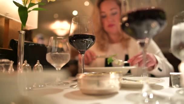 Mujer caucásica de unos 30 años disfrutando de una copa de vino tinto en el restaurante
. - Imágenes, Vídeo