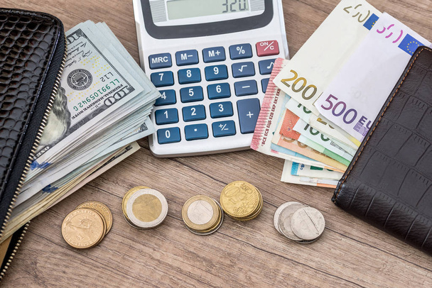 euro and dollar in purse with coin and calculator on desk. - Фото, изображение