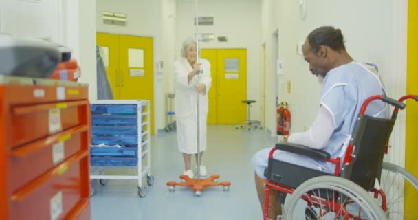 4K Surullinen mies istuu yksin hänen pyörätuoli kiireinen sairaala-alueella
 - Materiaali, video