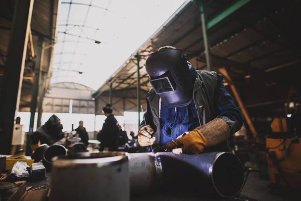  professionele lasser met bescherming masker werken in werkplaats - Foto, afbeelding