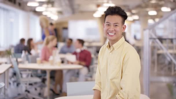 4k portret van lachende zakenman in kantoor met personeel in achtergrond - Video