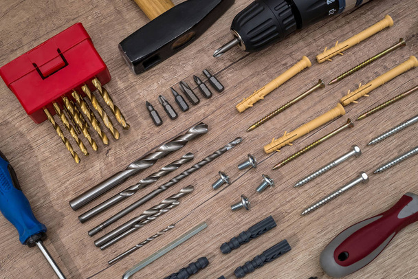 screw with dowel, screwdriver, hammer on desk. - Foto, afbeelding