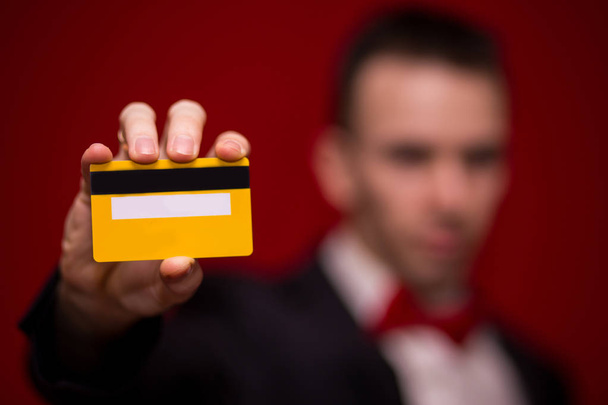Stylish man in suit hold credit card, with red background, focus on credit card. Payment concept - Fotografie, Obrázek