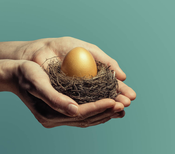Женщины осторожно держат гнездо золотым яйцом. Концепция экономии и увеличения экономии
. - Фото, изображение