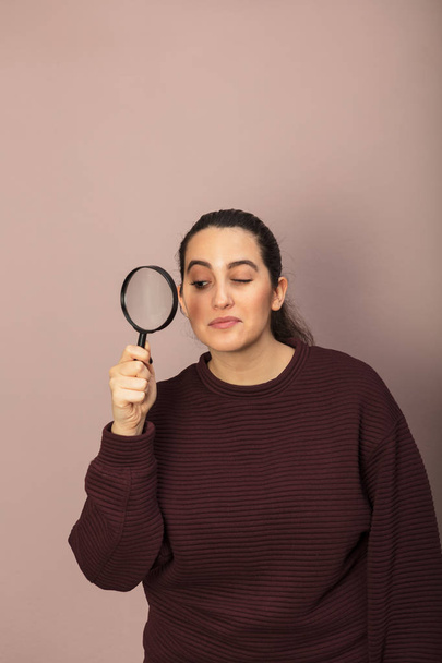 Young woman peering through a magnifying glass - Valokuva, kuva