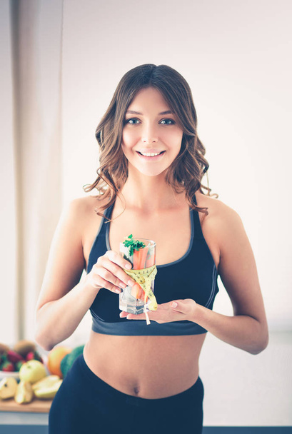 Woman holding a drinking glass full of fresh fruit salad with a tape measure around the glass. - Foto, immagini