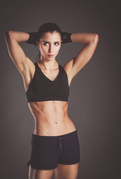 Muscular young woman posing in sportswear against black background - Fotoğraf, Görsel