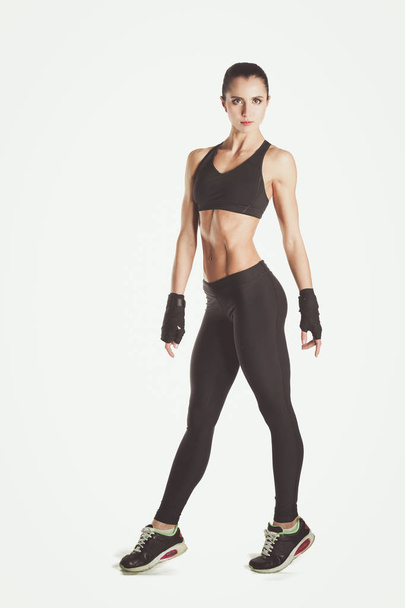 Muscular young woman posing in sportswear against black background. - Fotografie, Obrázek