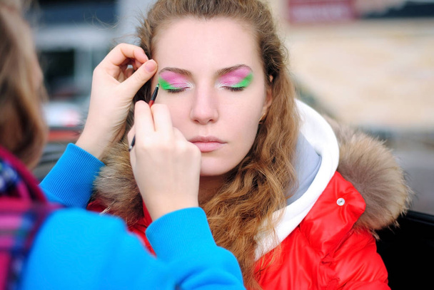 Make-up en cosmetica. Model. Een make-up artist doet make-up. Parkeerplaats. Achter de schermen - Foto, afbeelding