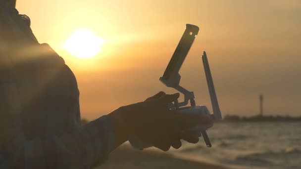 Womans ręce zarządzanie panelu sterowania drona o zachodzie słońca - Materiał filmowy, wideo