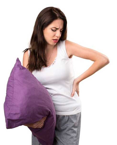 Όμορφη νεαρή κοπέλα με ένα μαξιλάρι με πόνο στην πλάτη - Φωτογραφία, εικόνα
