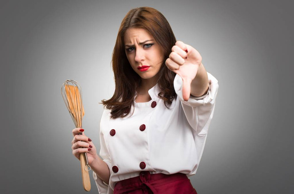 Όμορφη σεφ γυναίκα κάνει κακό σήμα σε γκρίζο φόντο - Φωτογραφία, εικόνα