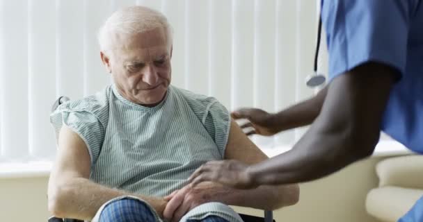 4K Caring medical worker speaking words of comfort to elderly man in wheelchair - Felvétel, videó