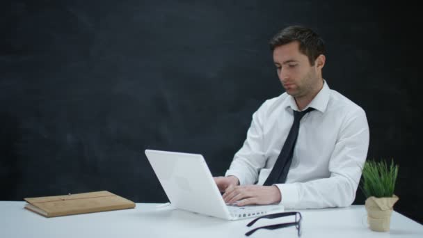 4K Pensive businessman working on laptop with chalkboard background - Πλάνα, βίντεο