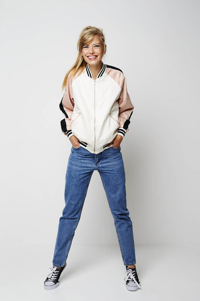 Girl wearing jeans and jacket standing and smiling at camera - Foto, afbeelding