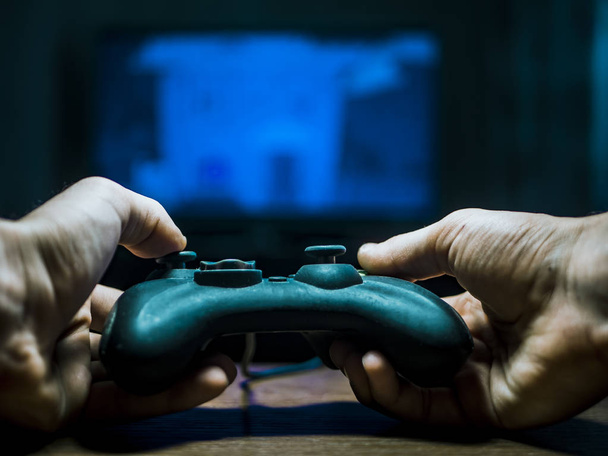 controlador de videojuegos joystick en las manos jugando en una televisión
 - Foto, imagen