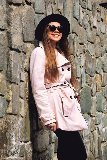 Ελκυστική νεαρή γυναίκα χαμόγελα χαρούμενα ακουμπά στον τοίχο - Φωτογραφία, εικόνα
