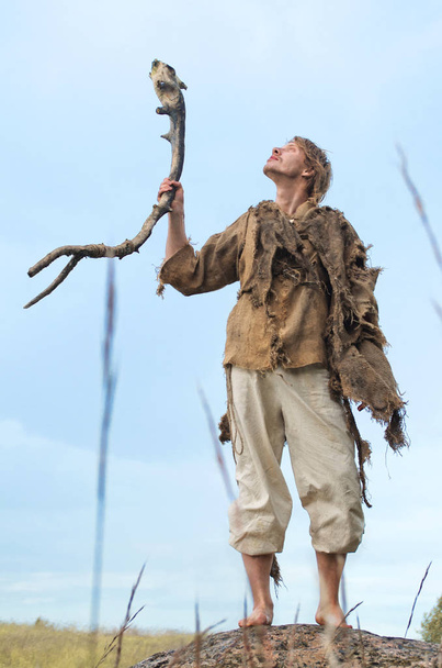 друид поднимает в небо деревянную палку
 - Фото, изображение