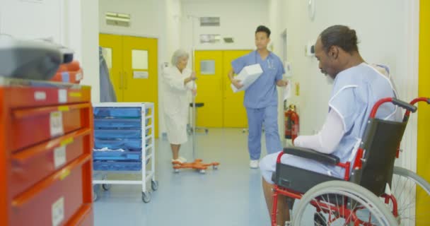 4 k smutný muž sedí sám v kolečkovém křesle v rušných nemocničních prostor - Záběry, video