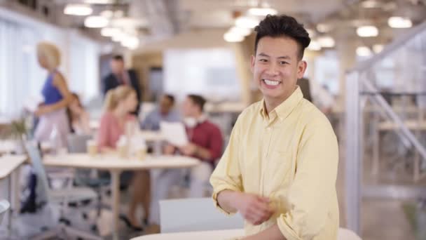 4K Retrato del hombre de negocios sonriente en la oficina con el personal trabajando en segundo plano
 - Imágenes, Vídeo