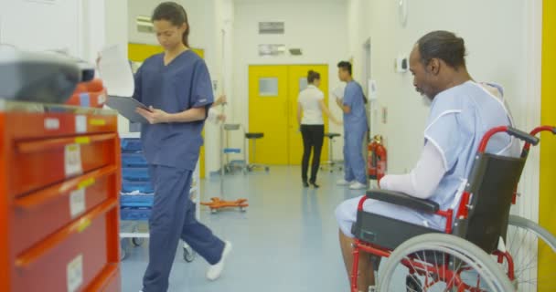 4k trauriger Mann sitzt allein in seinem Rollstuhl im geschäftigen Krankenhausbereich - Filmmaterial, Video