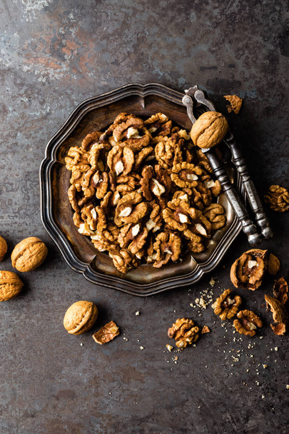 Walnut kernels and whole walnuts on rustic old wooden table - Photo, image